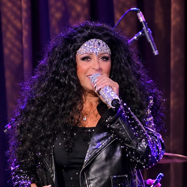 Sue Mondani, lead vocalist, singing in a rhinestone headpiece and studded leather jacket